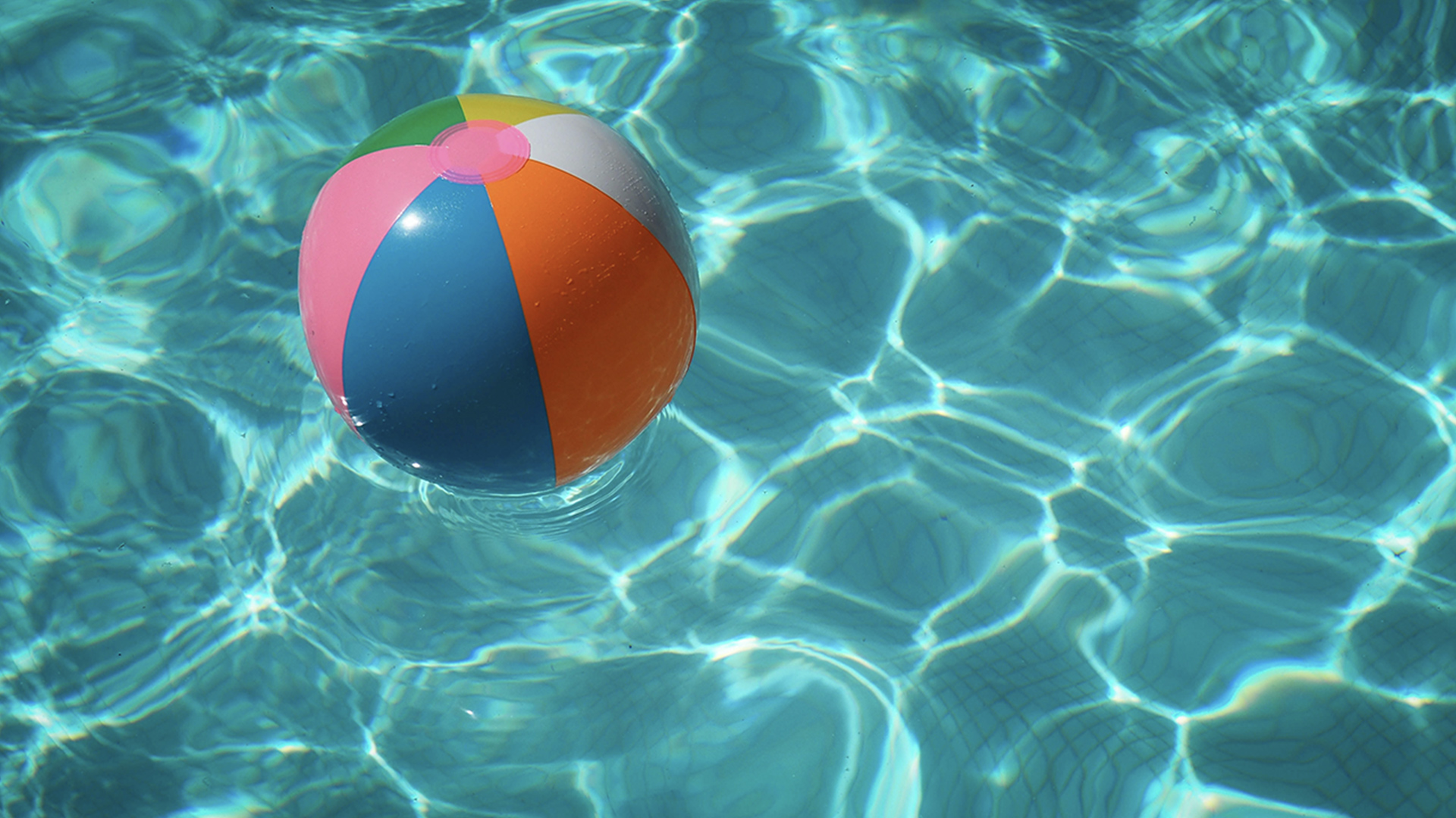 A blow up ball floating in a pool of blue water