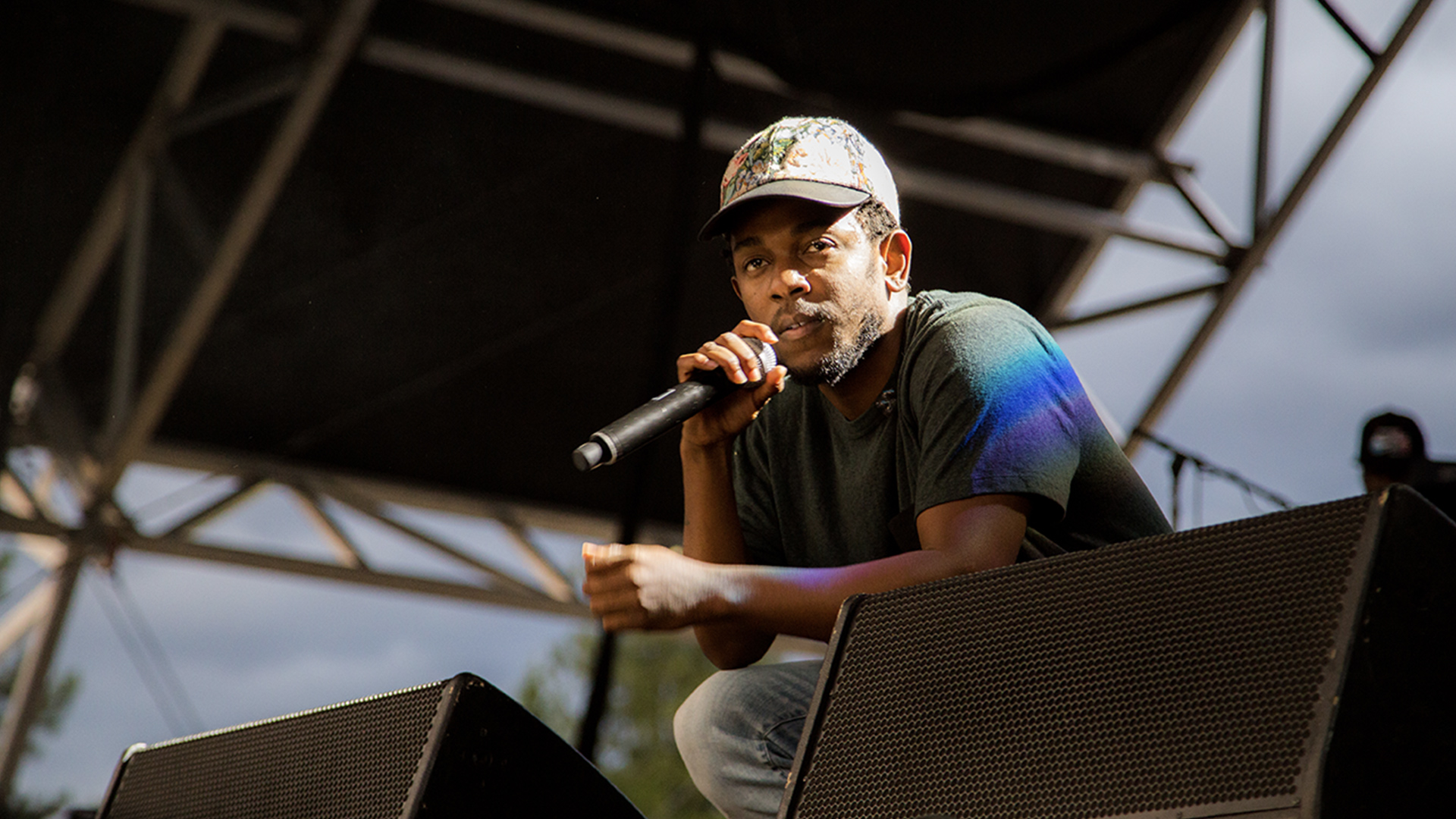 Kendrick Lamar crouched down near stage monitors