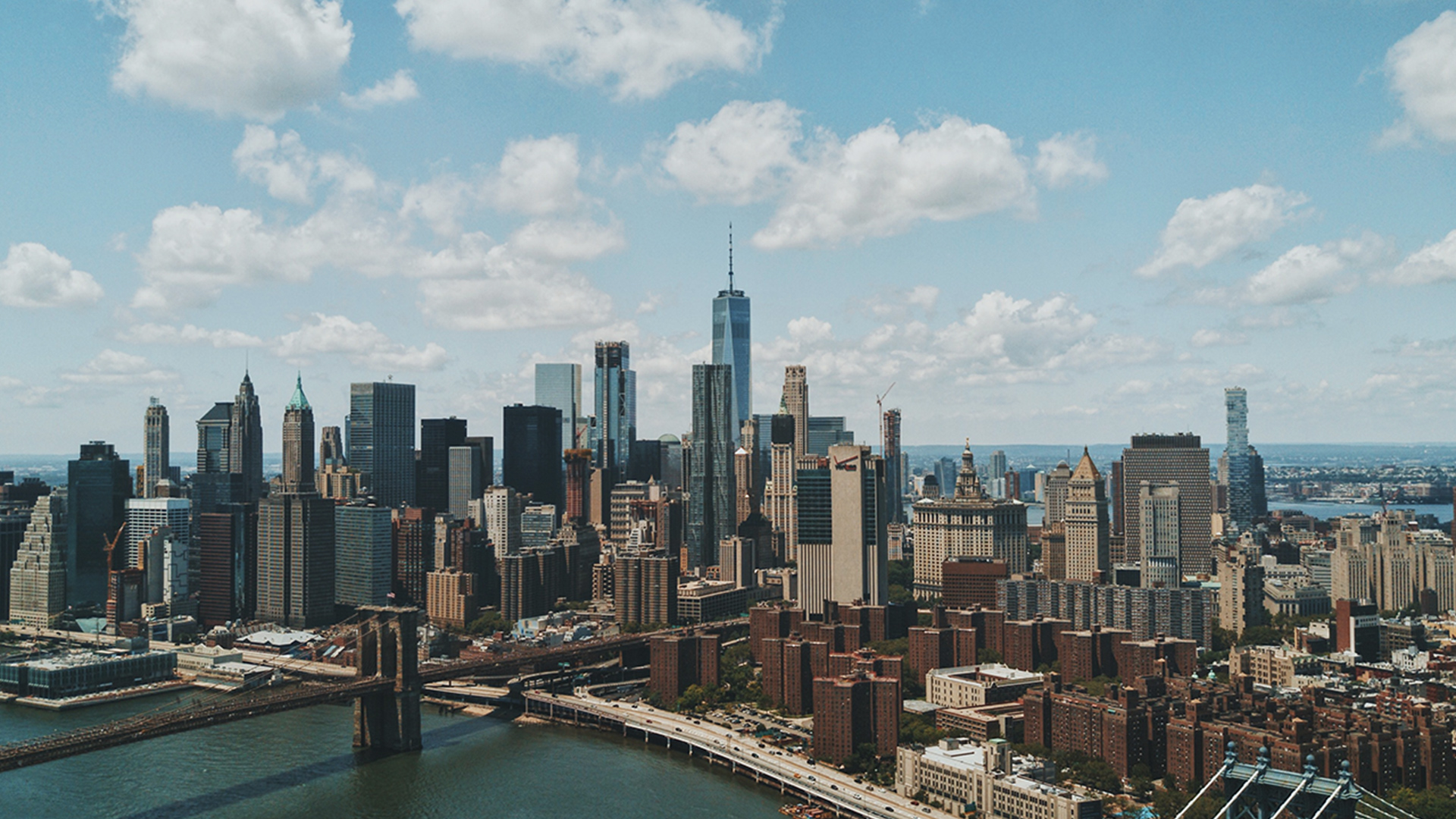 Brooklyn Bridge and New York City skyline under cloudy sky