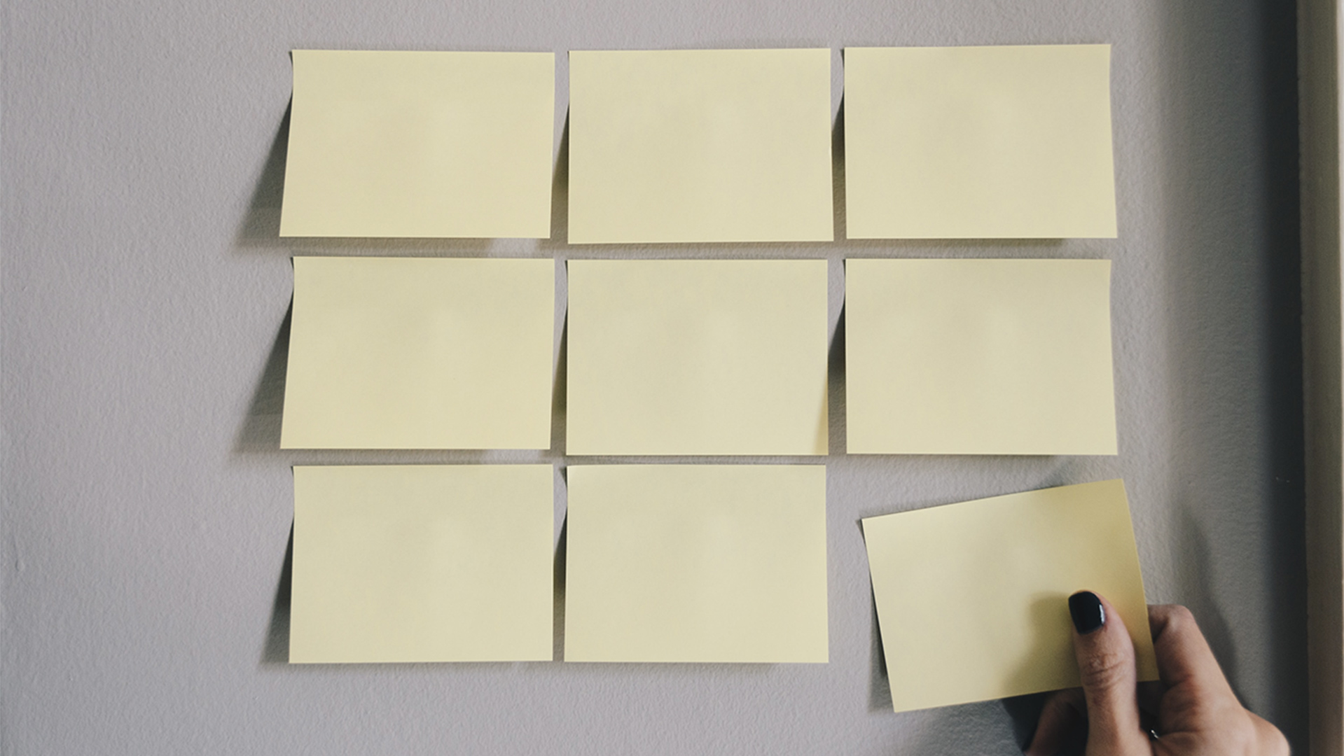 A person putting yellow post-it notes on a wall