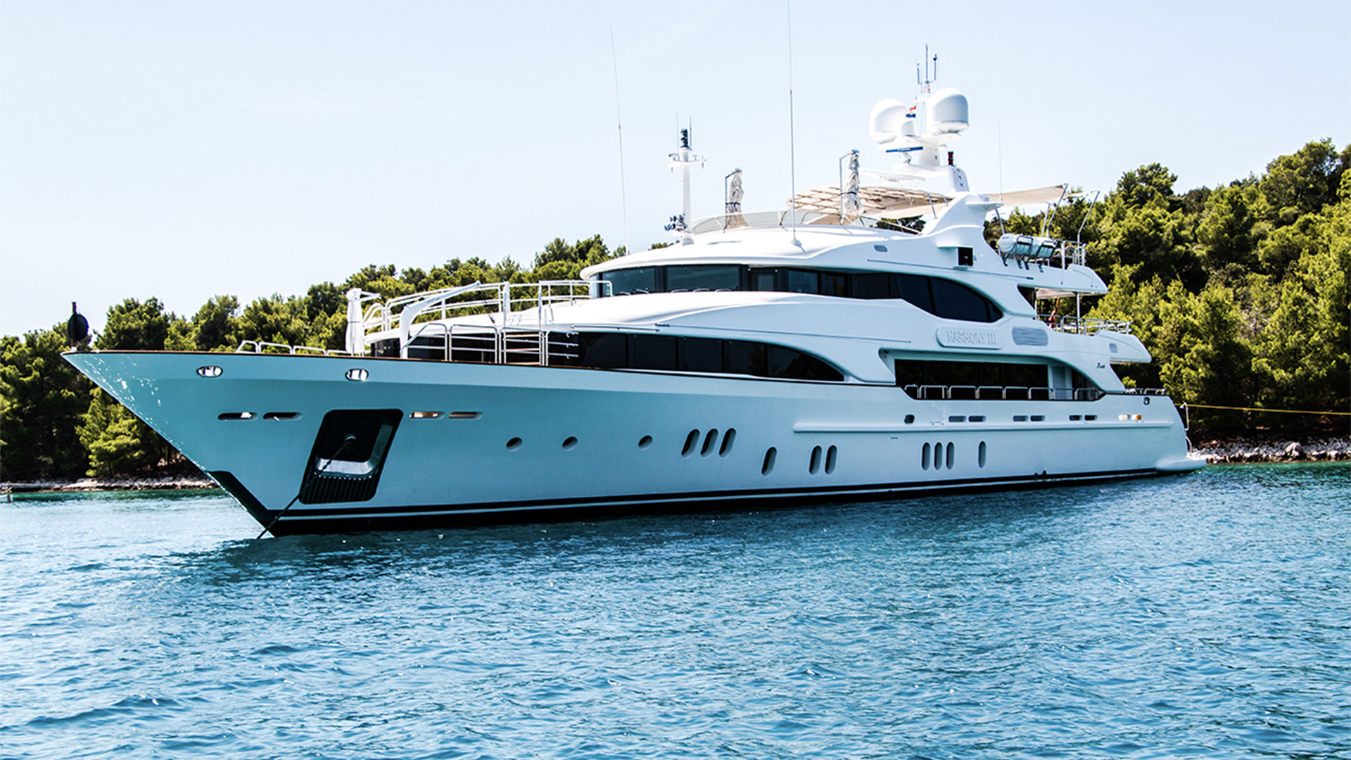 White and black yacht on body of water surrounded with tall and green trees