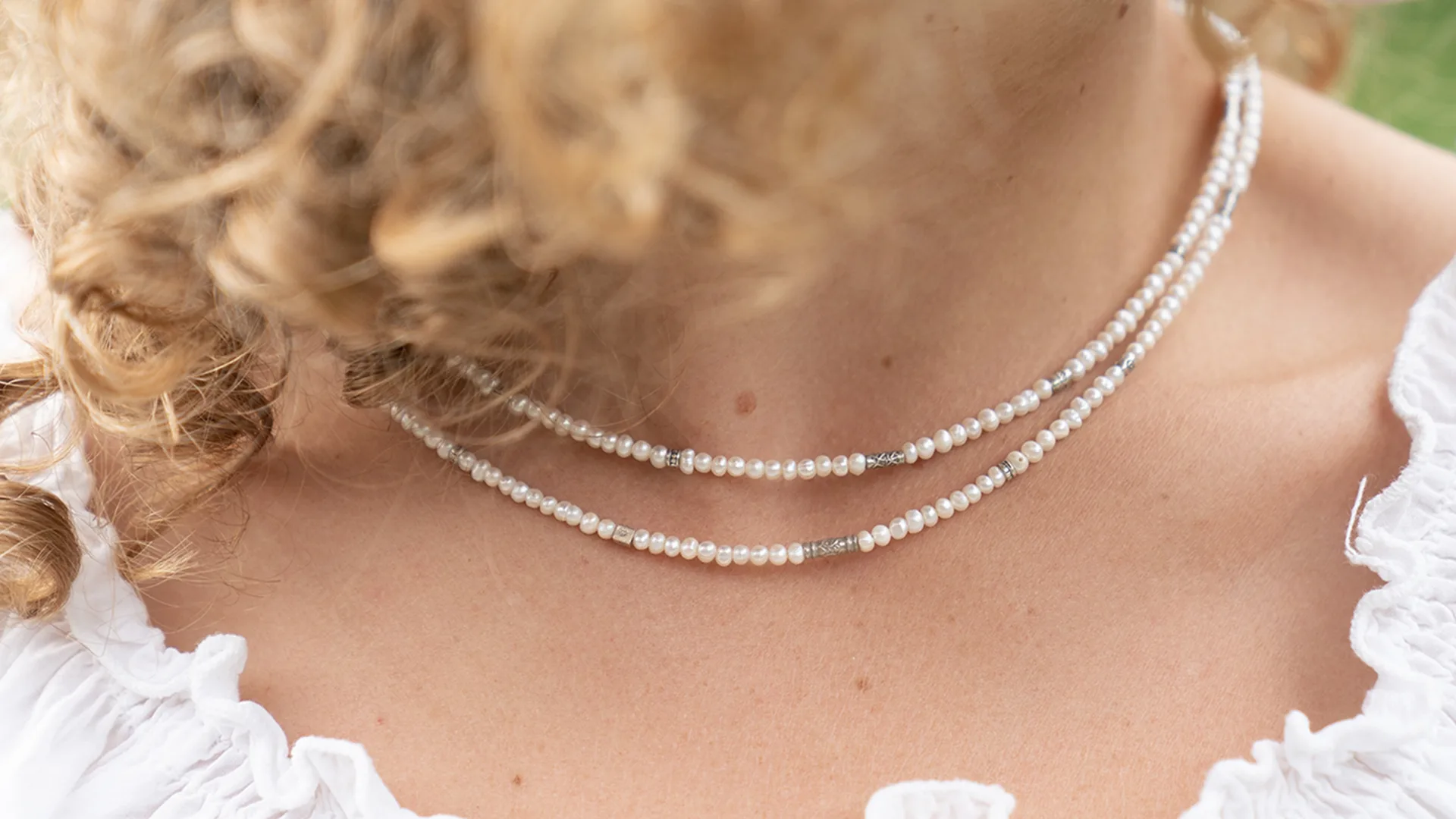 Close up of a woman wearing a white beaded necklace
