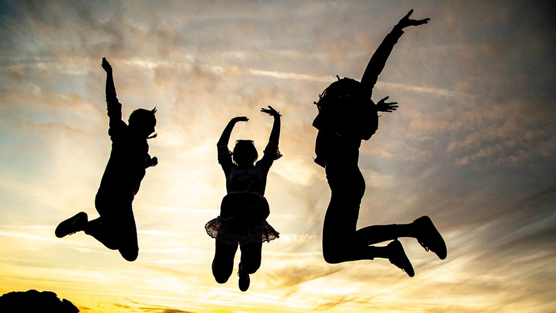 2 people jumping in the air against a lovely sunset