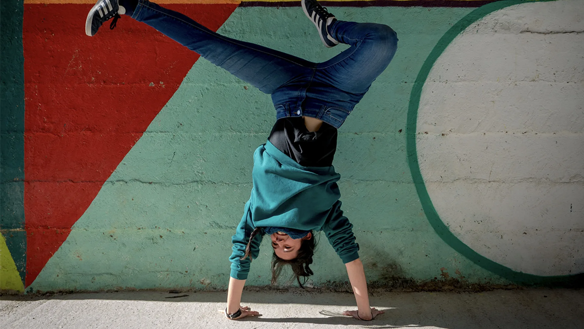 Woman dancing in front of a colourful wall