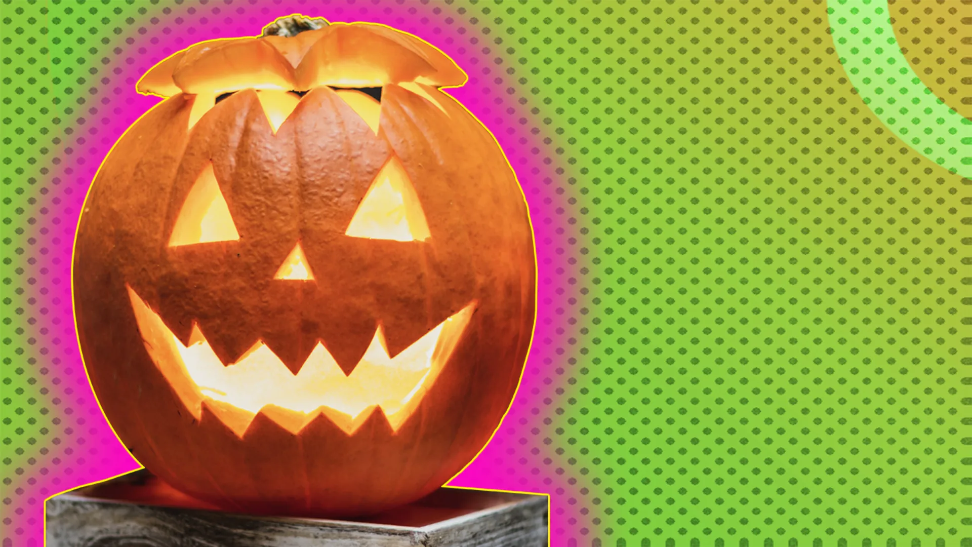 Carved pumpkin placed on box, outlined by pink halo effect on green-dotted background.