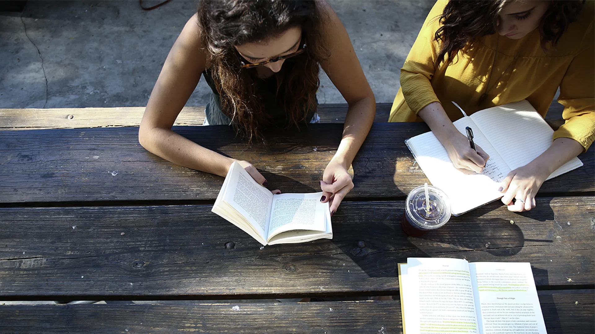 Three young people working and reading outside at a bench from an arial view