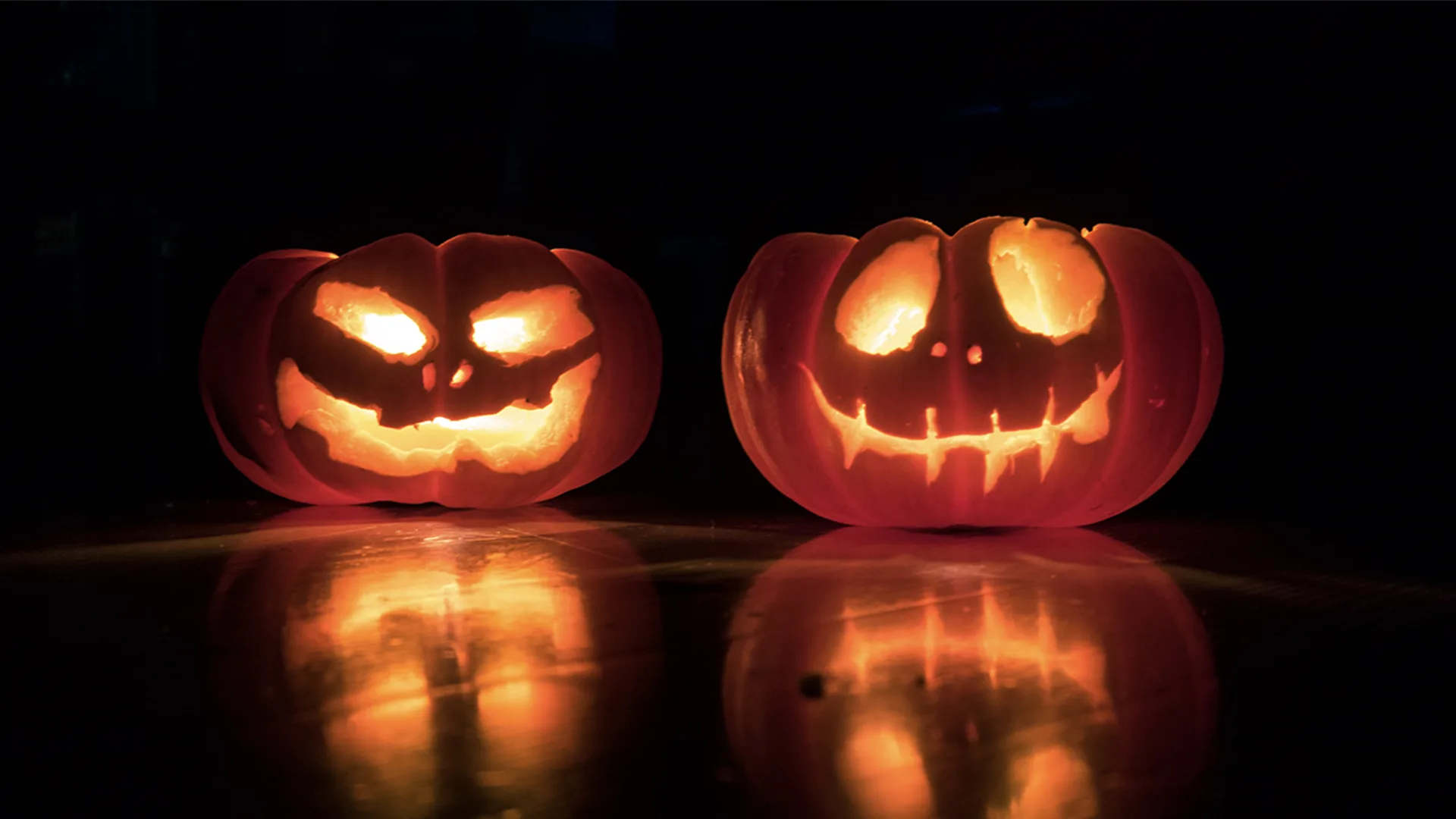 Two carved pumpkins lit up by a candle