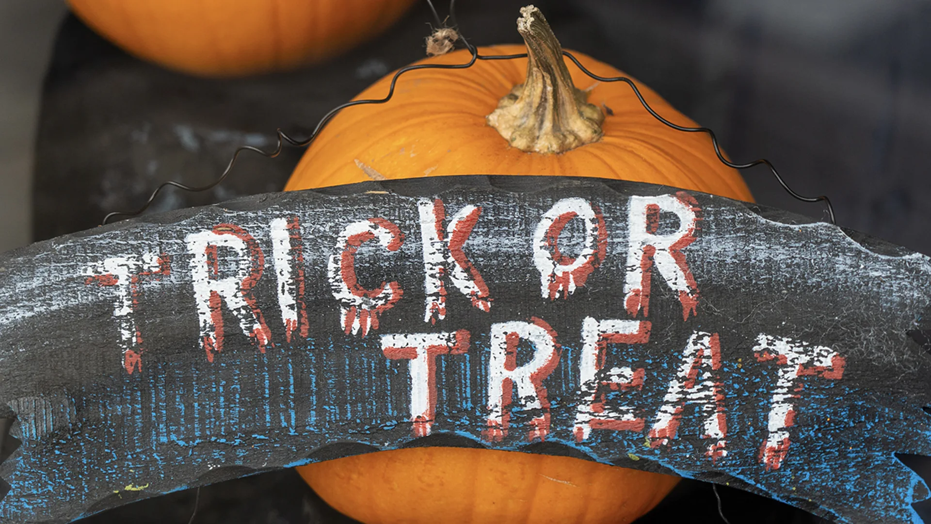 Trick or treat sign over a pumpkin