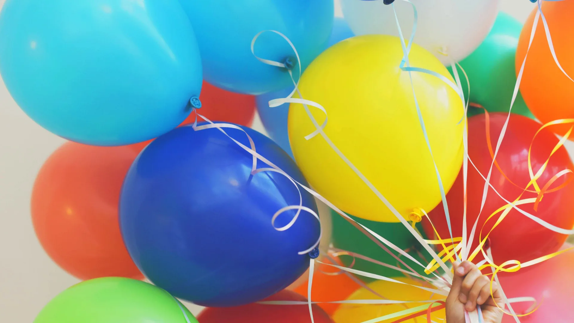 Hand holding many coloured balloons