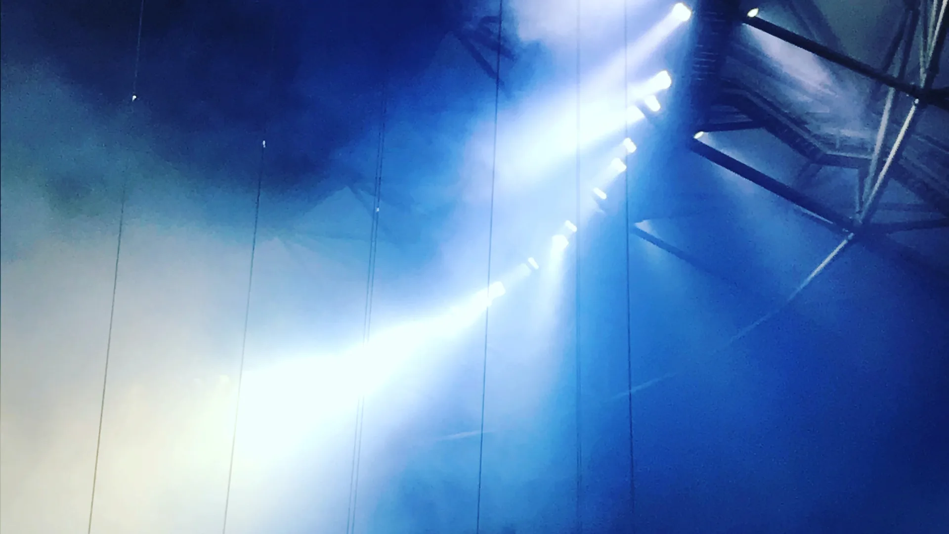 Blue and white lights on a stage rig against a dark sky