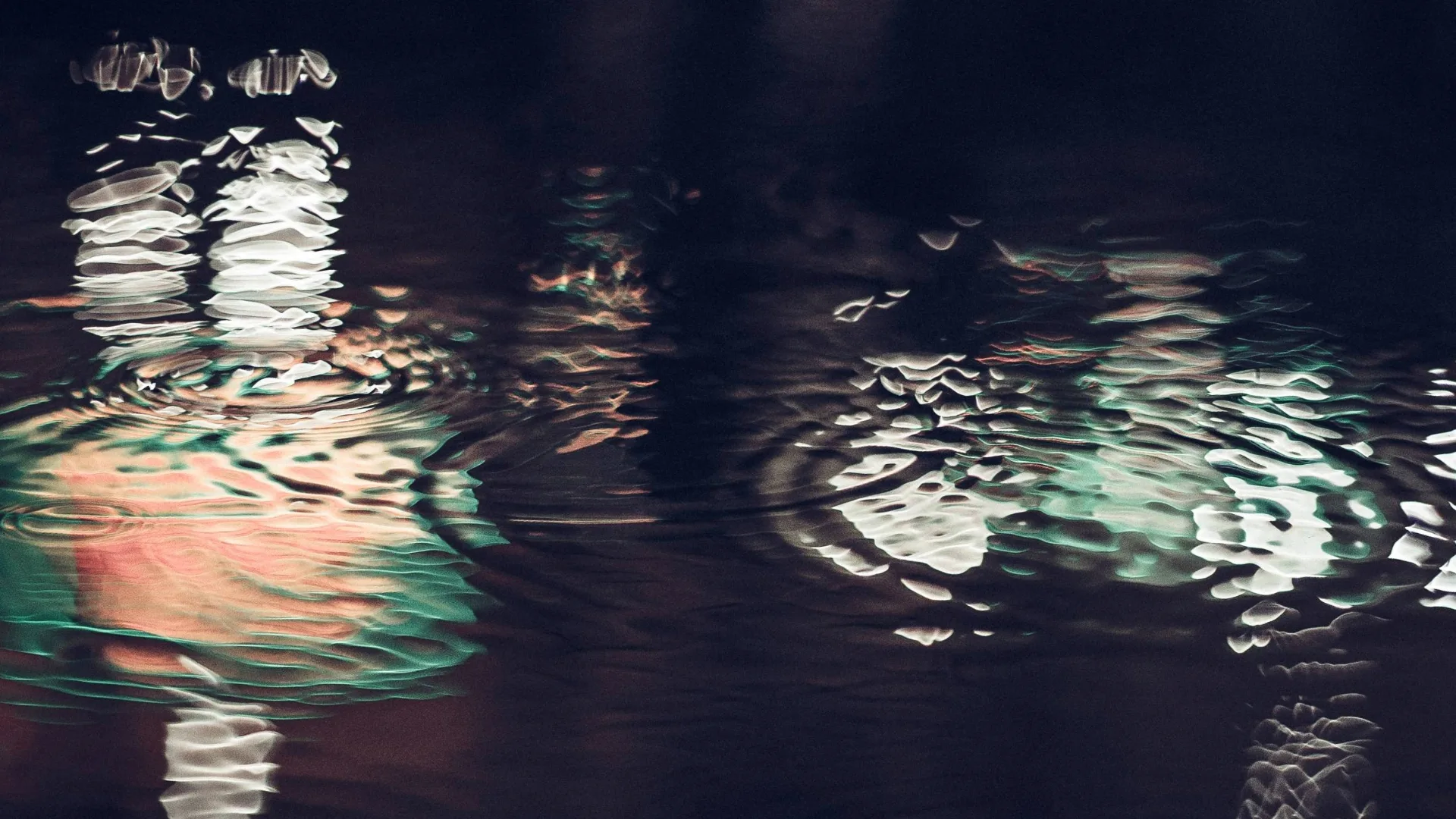 Reflections of coloured lights in a black body of water