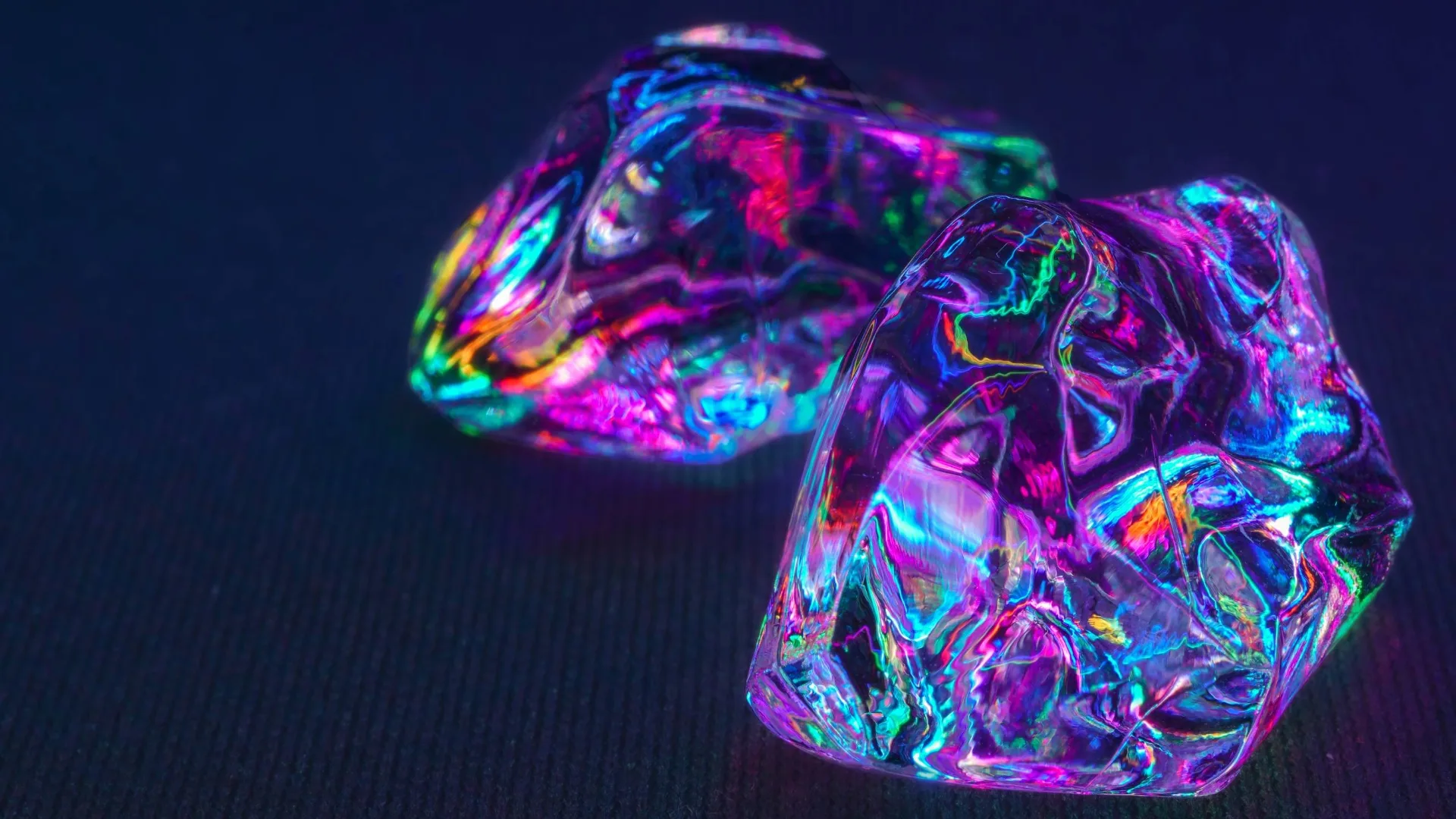 Mulitcoloured neon ice cubes on a black background looking like they glow