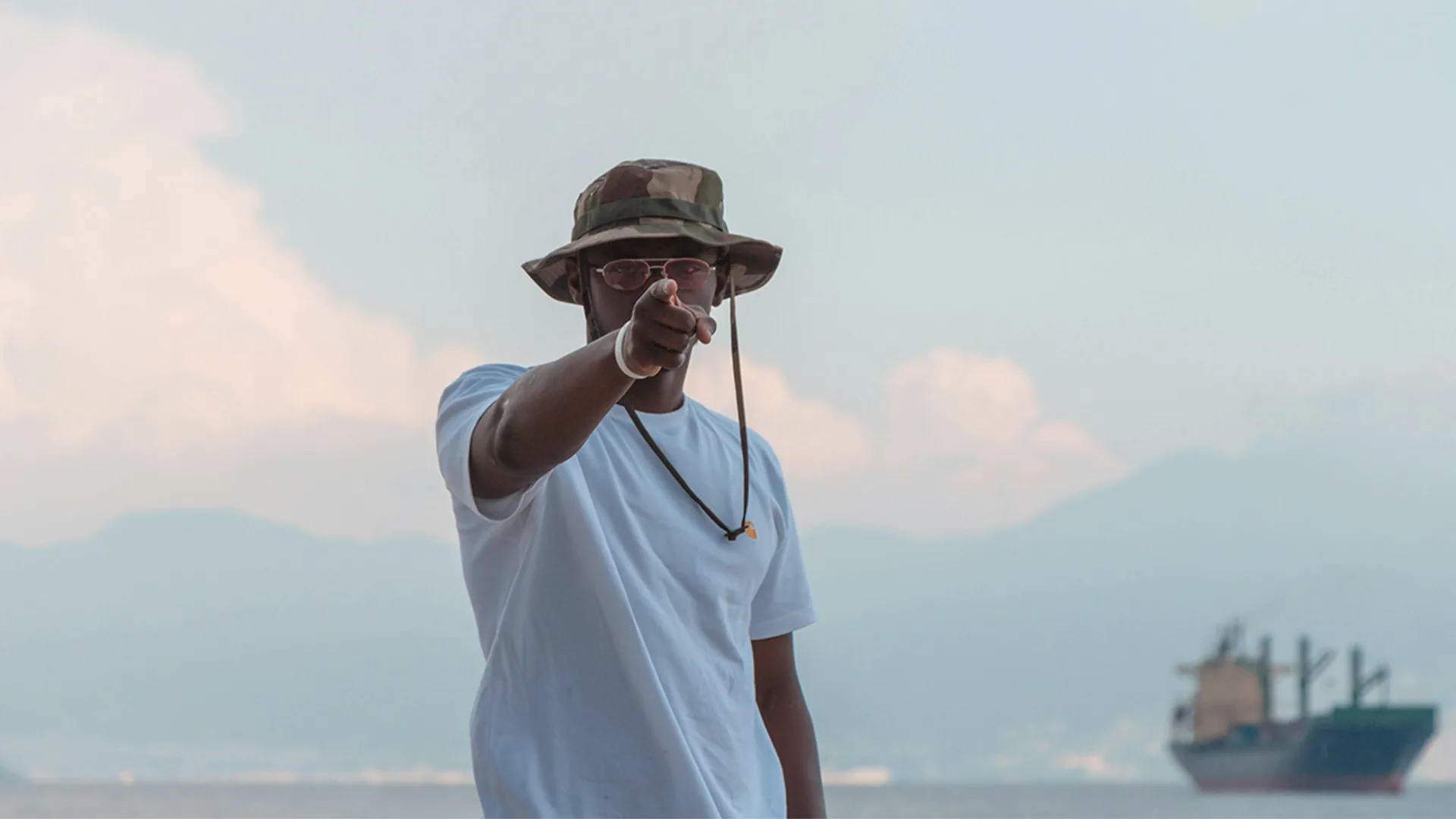 A man in a green hat and white top pointing