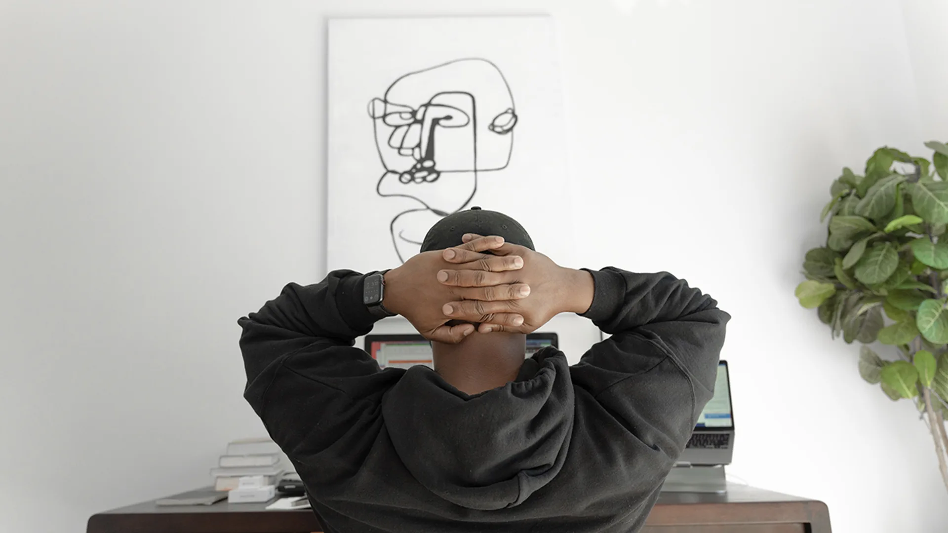 A man in a black hoodie looking at a computer