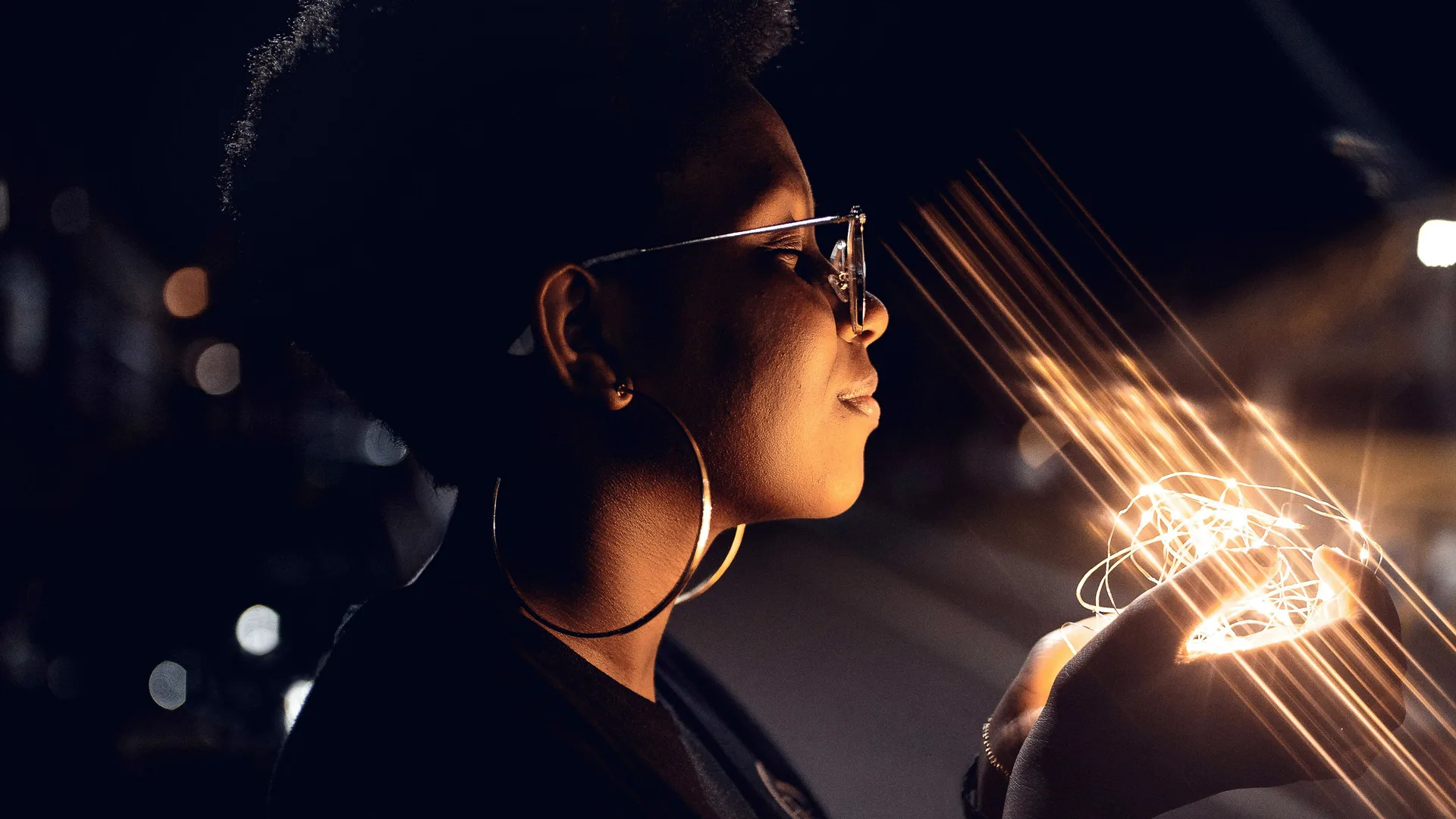 A photograph of a woman holding string lights