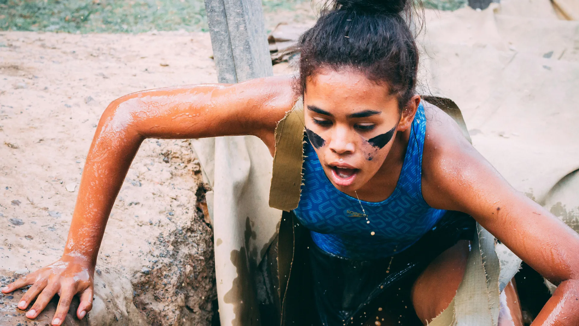 Photograph of a woman pulling herself up in a obstacle course challenge