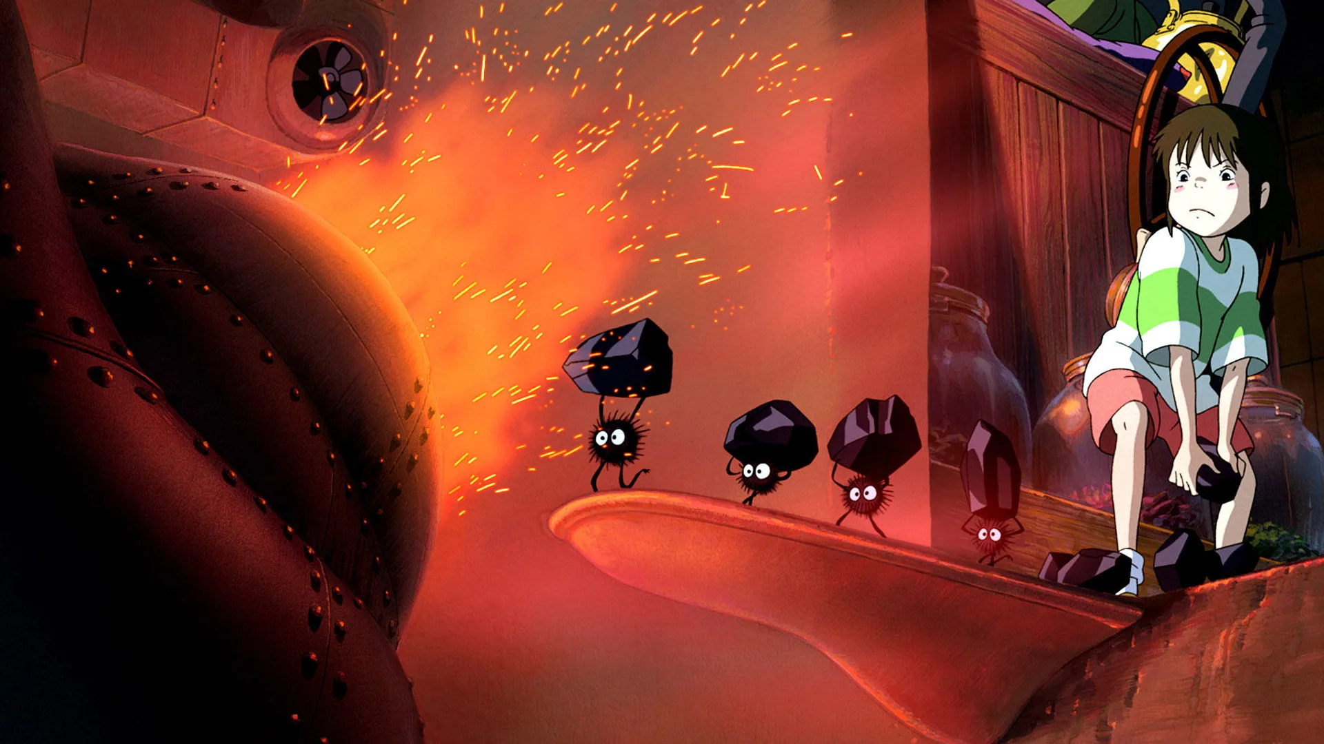 A still from the film Spirited Away showing Chihiro pushing soot into a fire