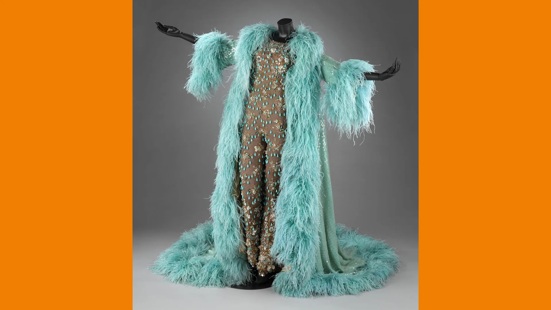 A photo of a turquoise feather coat over a gold glittering jumpsuit against a grey background with orange borders