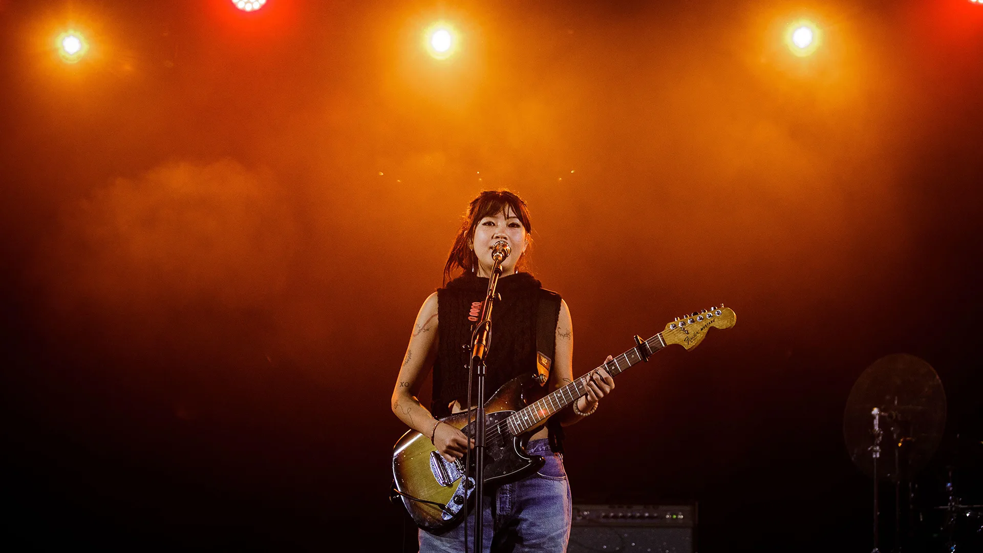 Singer beabadoobee performing on stage with guitar under orange lights