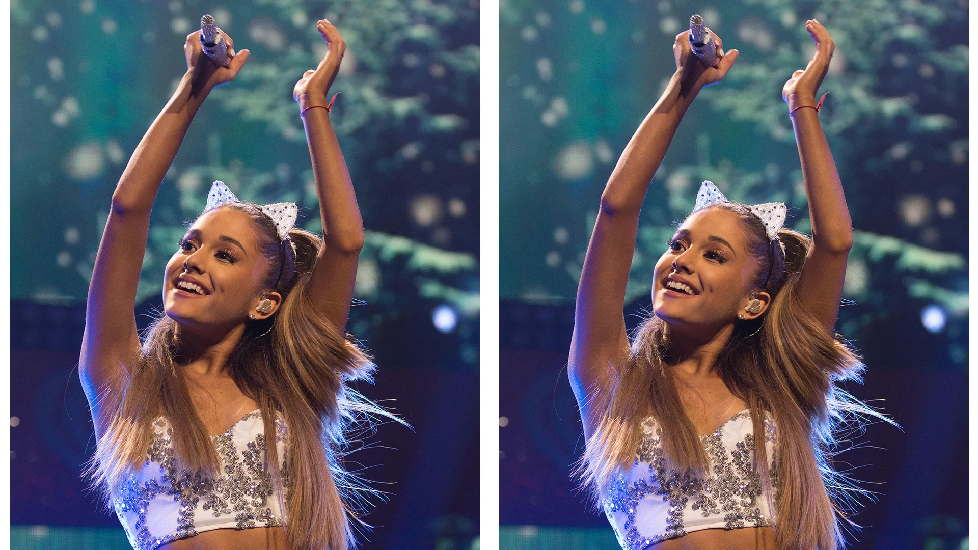 Ariana Grande onstage wearing a white outfit with cat ears, she's holding a microphone and clapping her hands