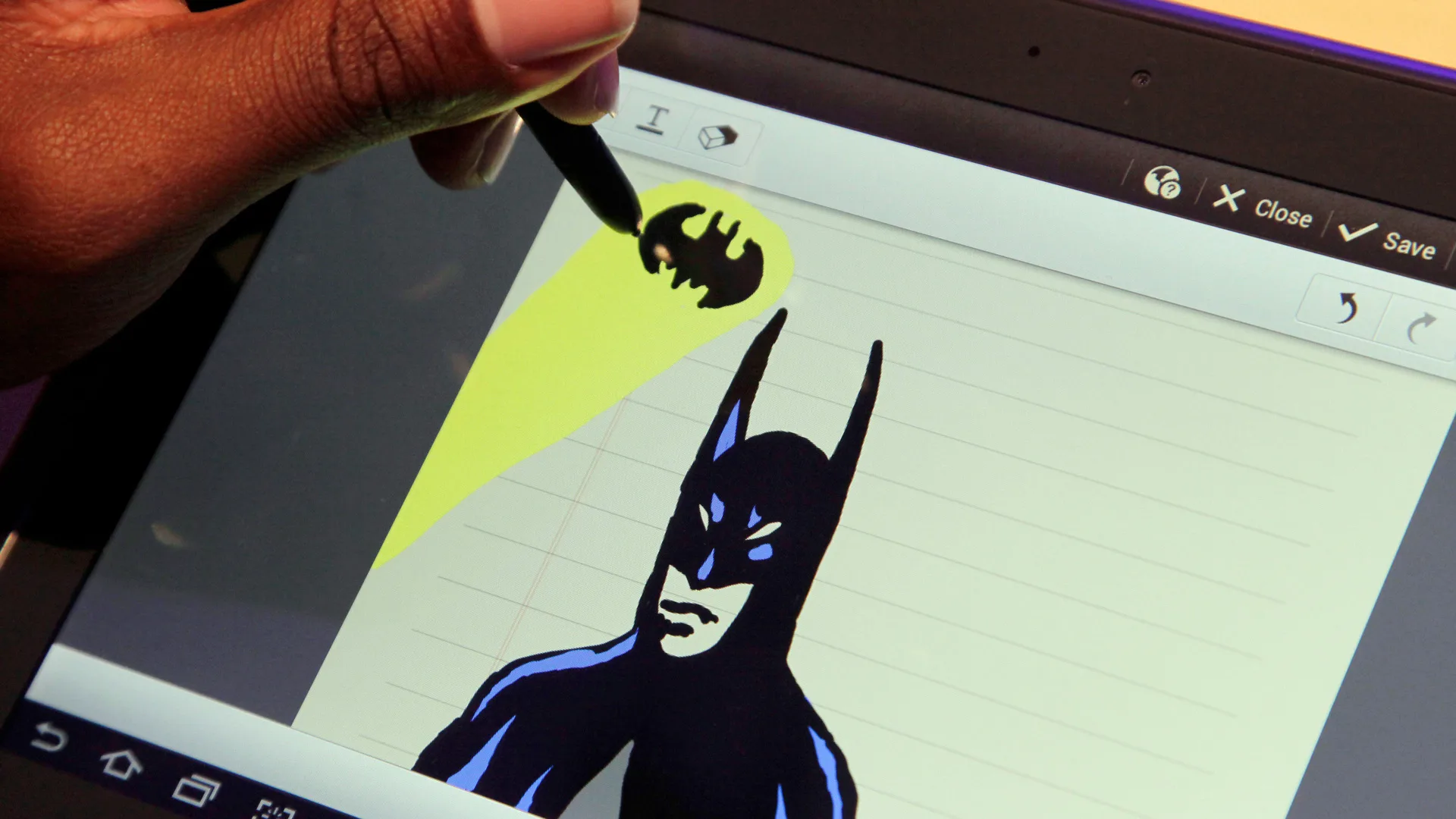 A photo of someone using the first galaxy note drawing a picture of batman on the screen