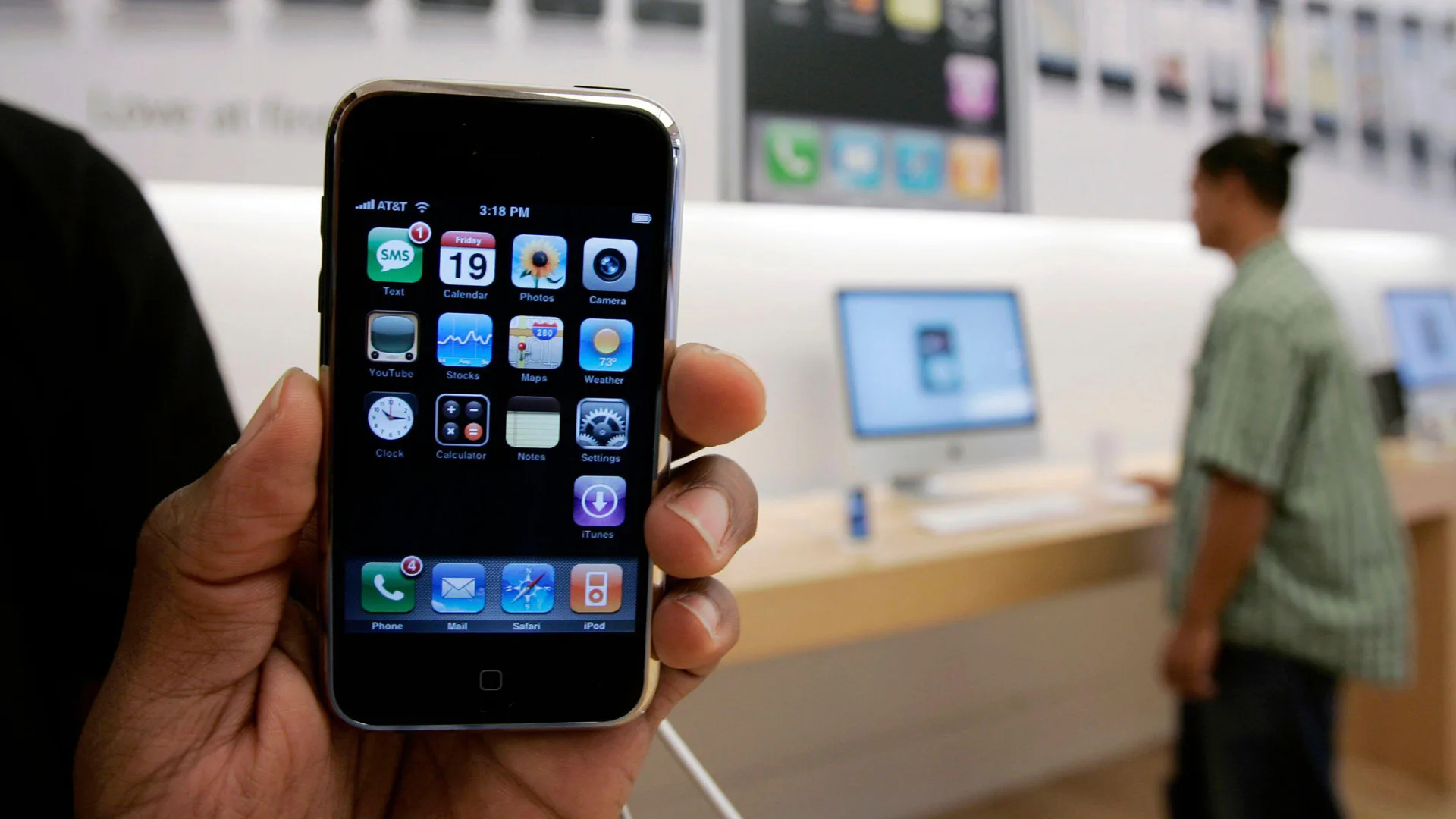 A photo of the first iphone being held by a hand in the apple store