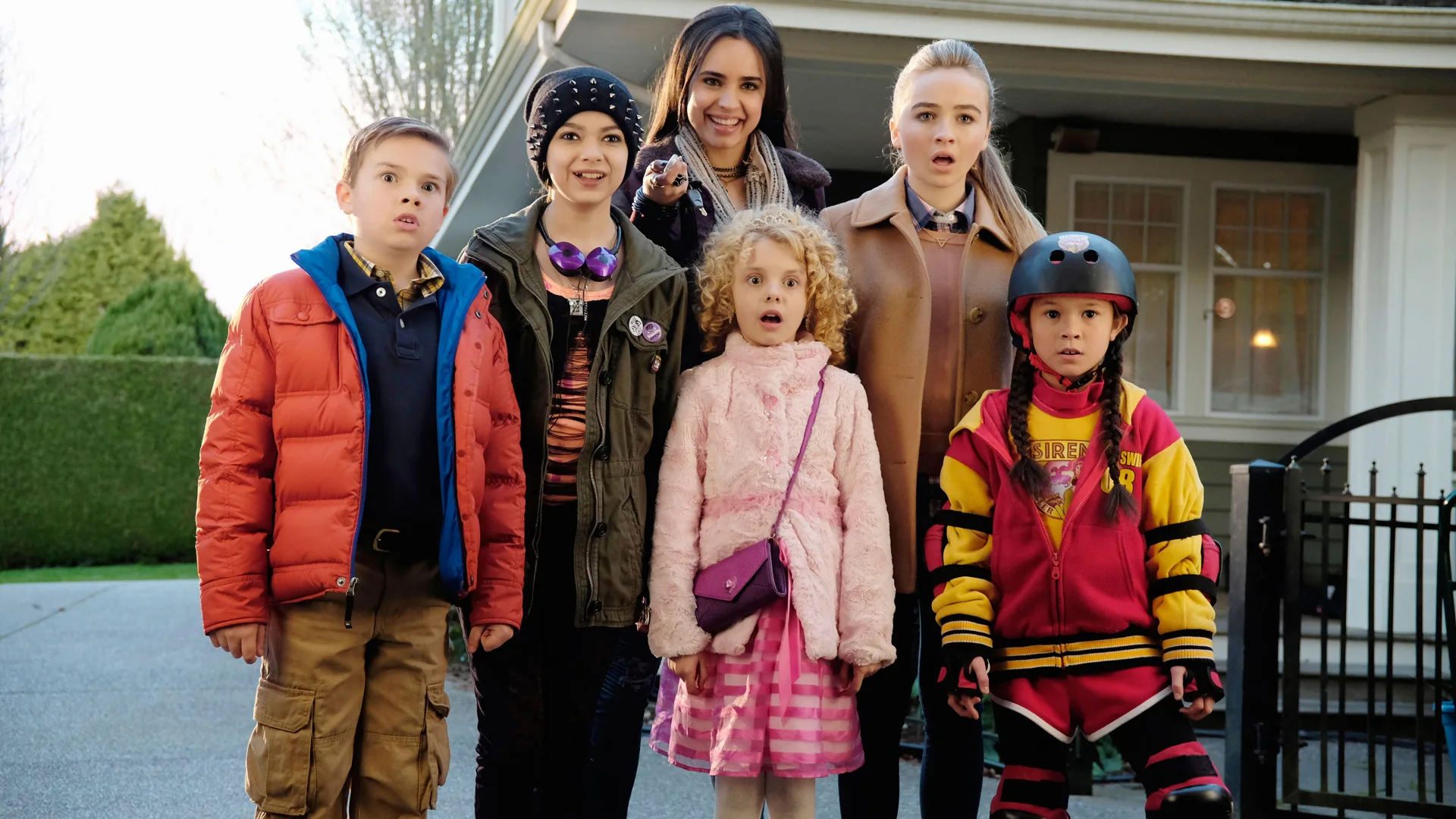 A photo of Sabrina Carpenter and Sofia Carson with the actors in Girl Meets World. They're stood on a street outside a big house with surprised faces.