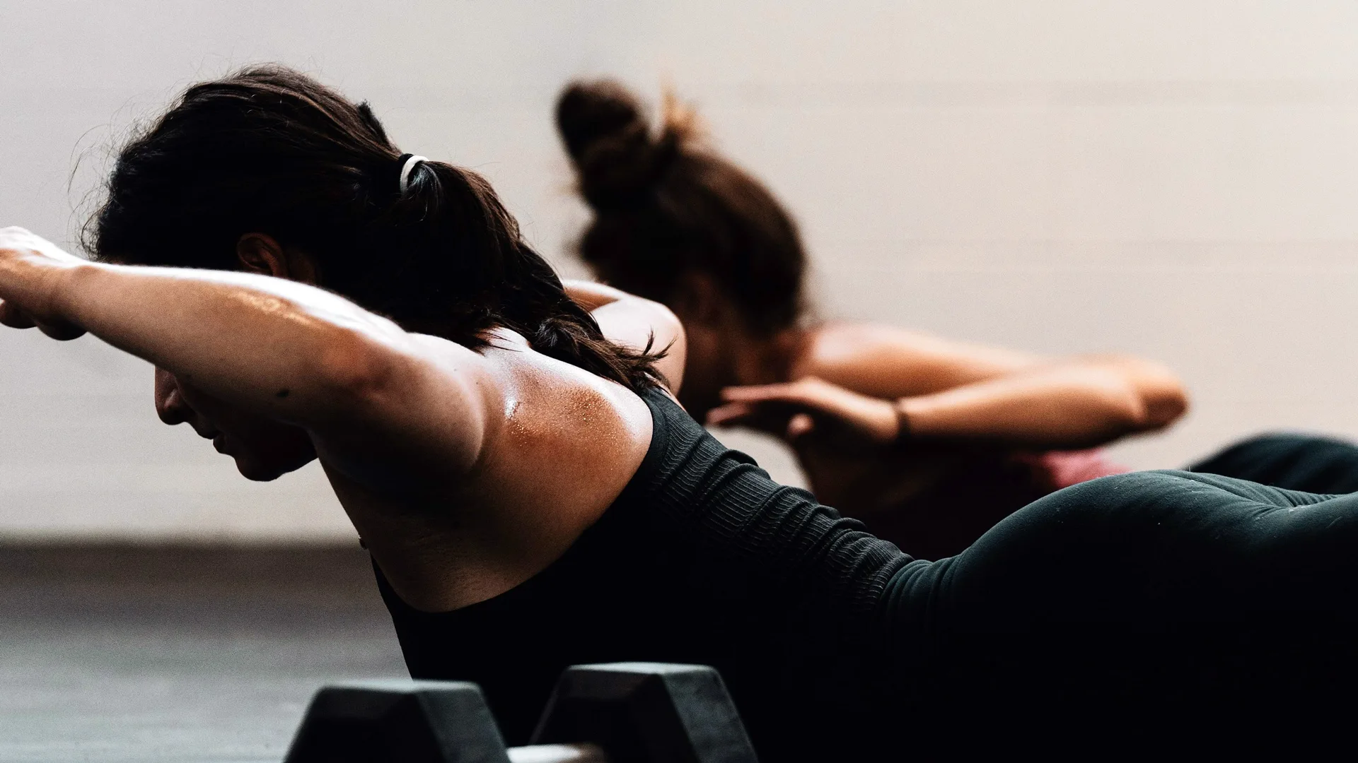 A photo of two women doing a floor workout with weights